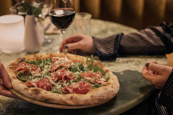 pizza being placed on a restuarant table